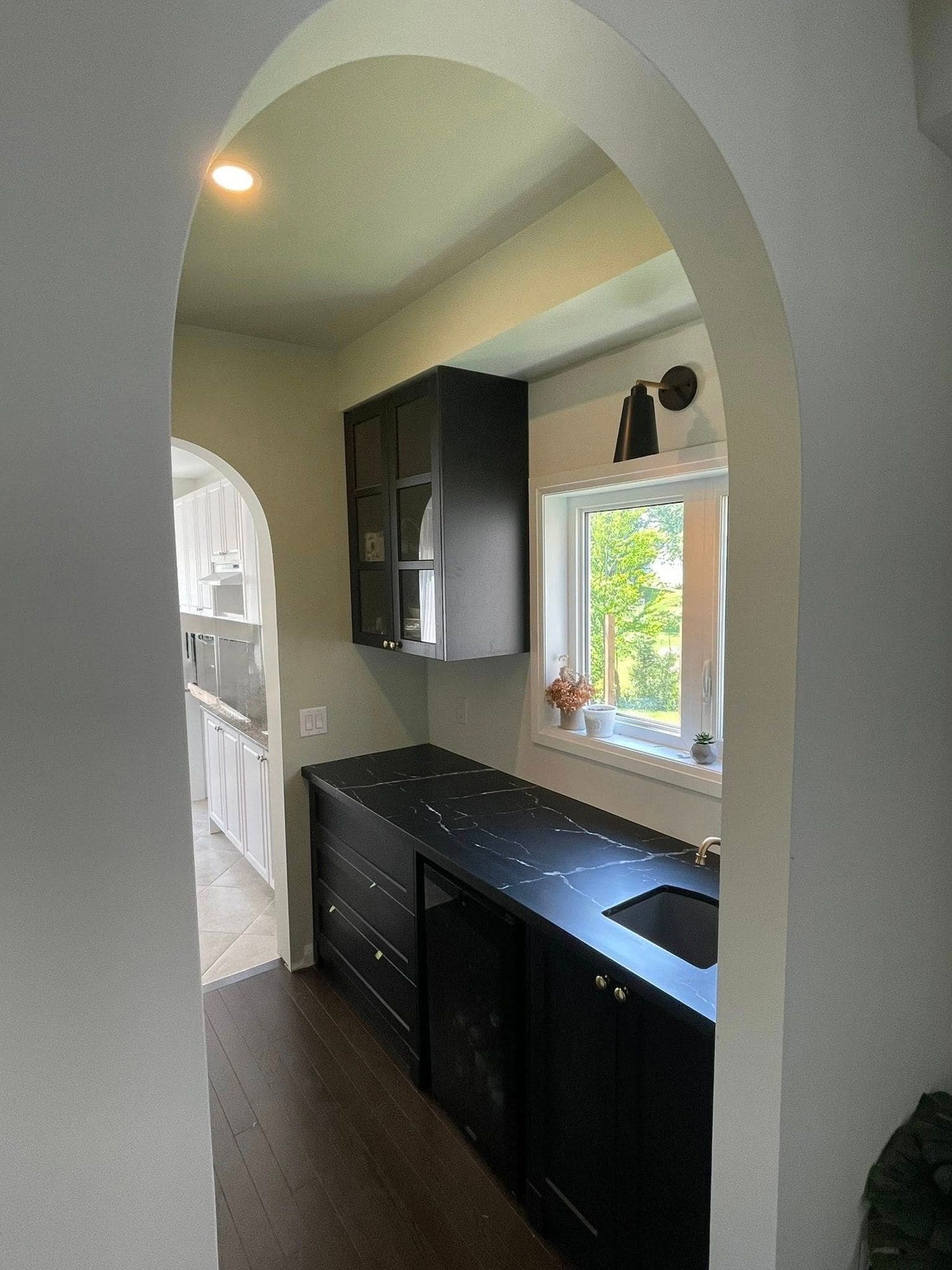 Arched doorway with custom black cabinetry and marble countertop, finished by Elevation